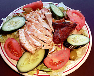 Sliced bbq'd chicken breast on garden fresh salad plate